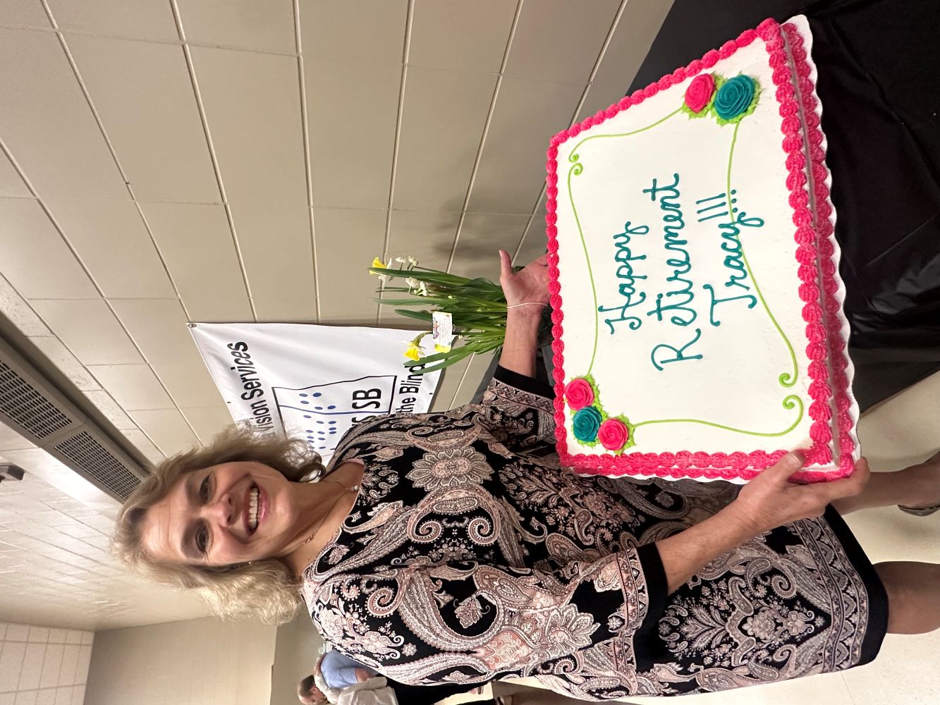 Tracy smiles as she holds her retirement cake.